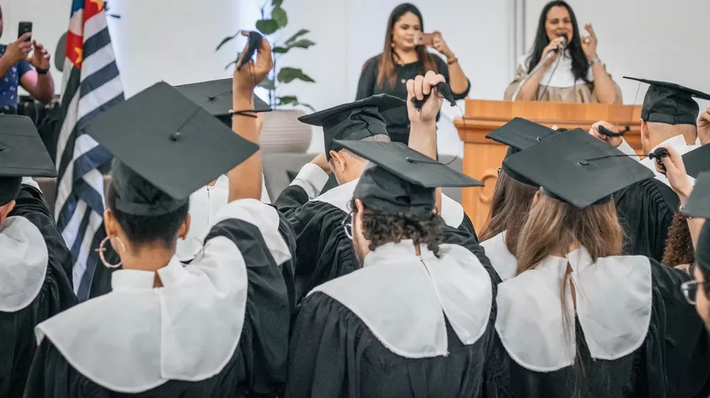 Formandas de beca e capelo durante a cerimônia de formatura